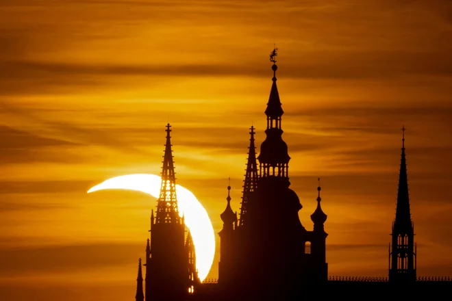 Luna delno zakriva sonce med sončnim mrkom nad Praškim gradom, kot je bilo posneto iz Prage na Češkem. FOTO: Eva Korinkova/Reuters