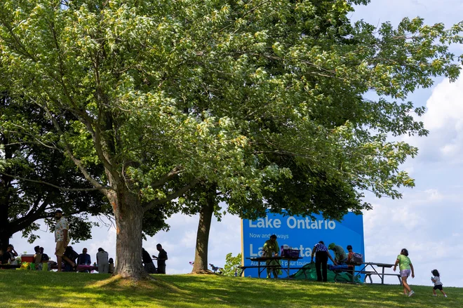Ljudje sedijo ob napisu »Jezero Ontario, zdaj in za vedno«, ki ga je premier Ontaria Doug Ford razkril v naravnem parku Fifty Point. FOTO: Carlos Osorio/Reuters