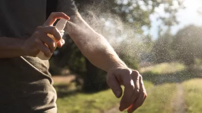 Prevention against mosquito bite during sunny summer day. Man is applying insect repellent on his hand.
