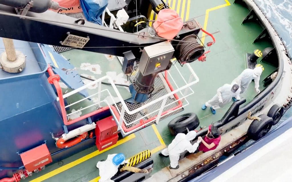 Investigators wearing white suits searching the deck of the infected MV Hondius. AP