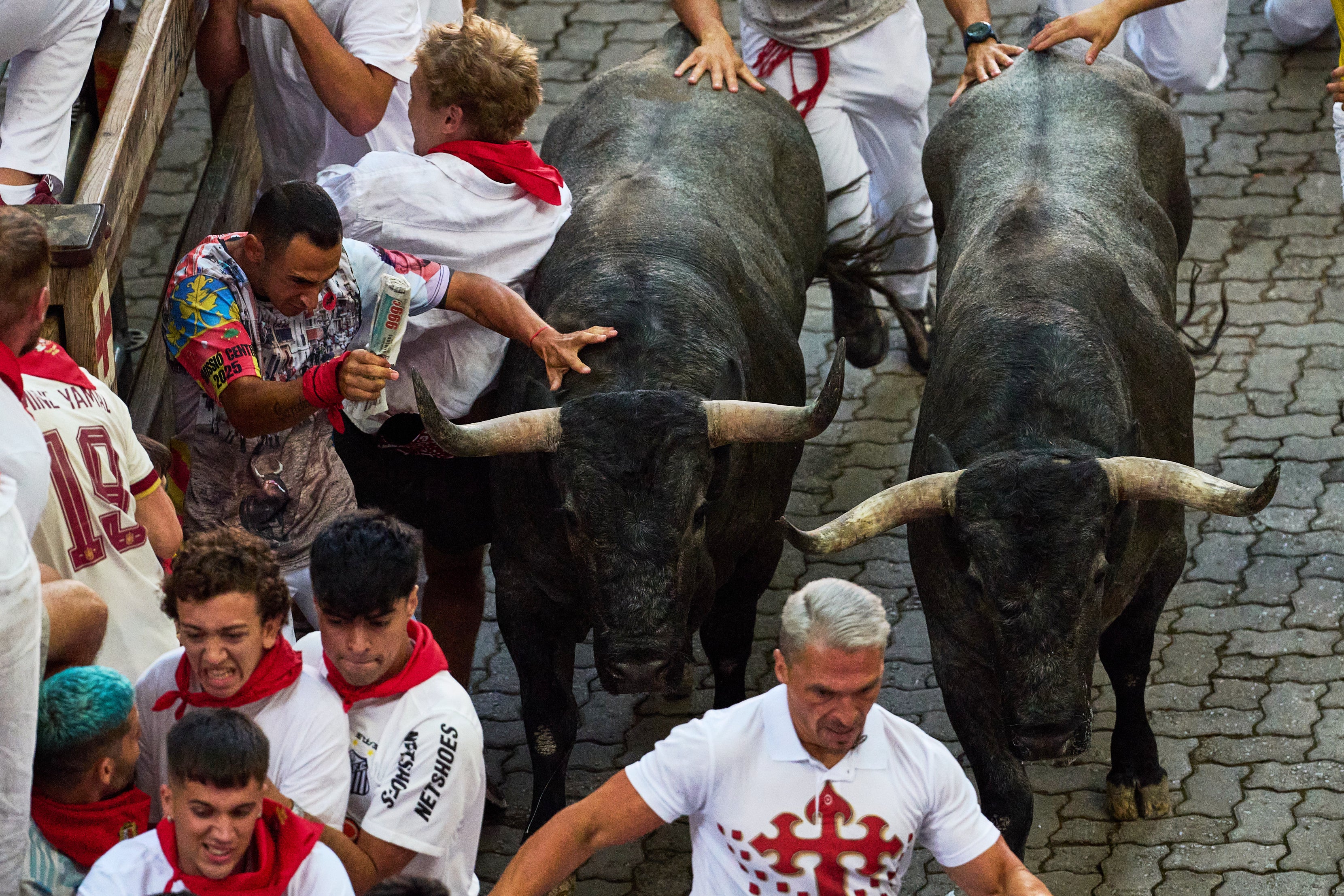 Revelers run alongside Jose Escolar's fighting bulls during the fifth running of the bulls at the San Fermín festival in Pamplona, Spain, Saturday, July 11, 2026. (AP Photo/Miguel Oses)