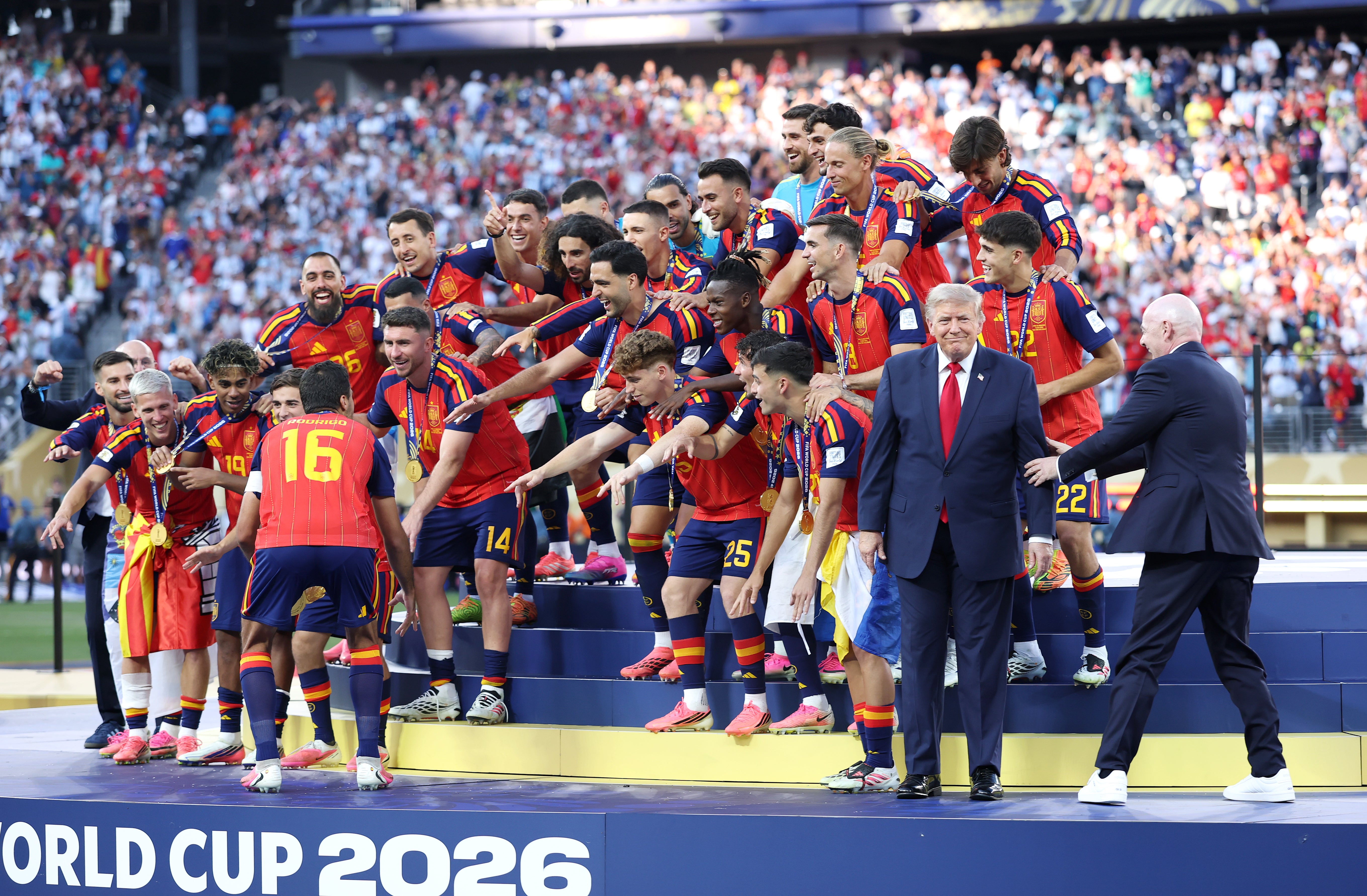 Fifa president Gianni Infantino attempts to usher Donald Trump away from the victorious Spain team as they lift the 2026 World Cup