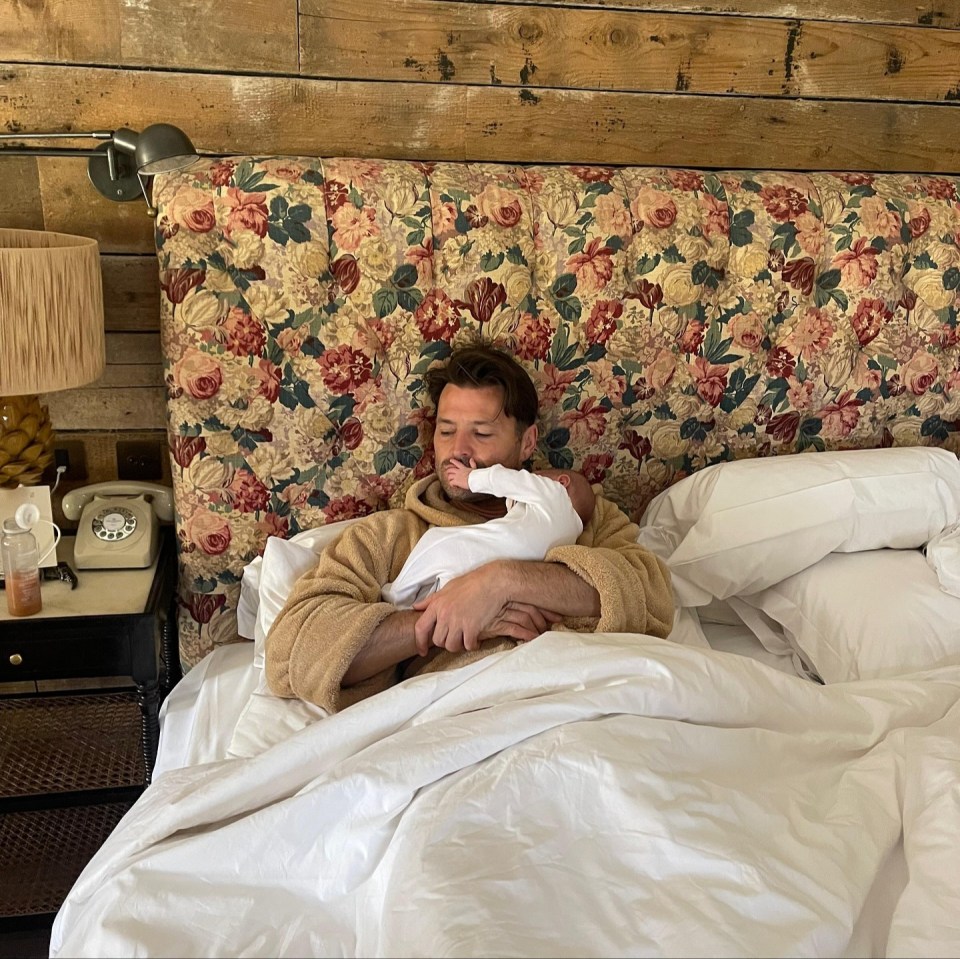 Man in a robe holding a baby in bed.