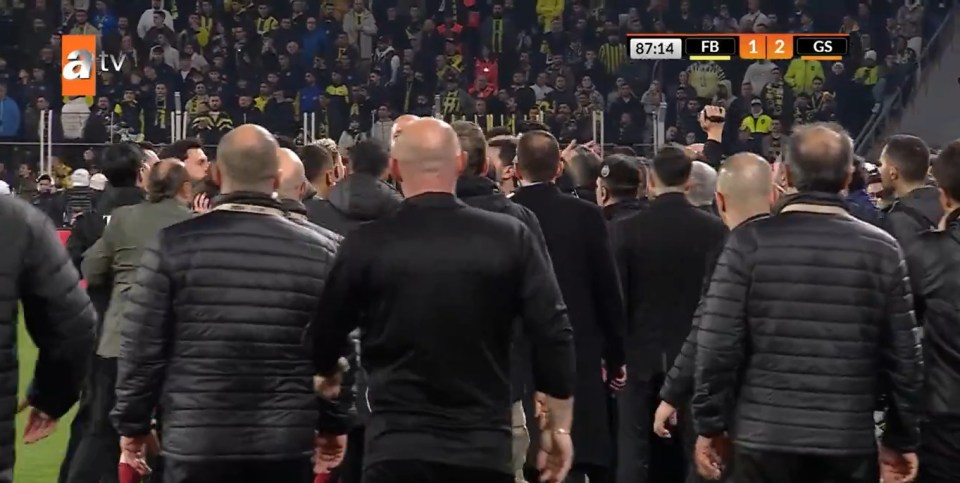 Screenshot of a soccer game, showing the back of a group of people walking away from the camera.