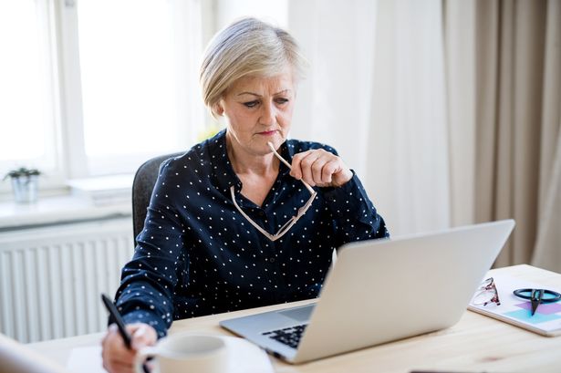A confident female pensioner using computer indoors.