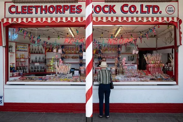 A woman buys a some rock from a beach front stall, in the sunshine in Cleethorpes, north east England on July 7, 2023 (Photo by Oli SCARFF / AFP) (Photo by OLI SCARFF/AFP via Getty Images)