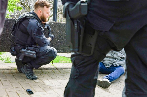 Police officers arrest a man at the side of St James Barton Roundabout