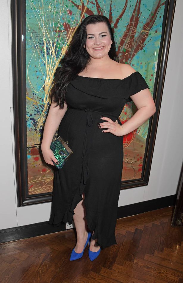 Charlotte Jaconelli posing in a black dress and smiling at an event