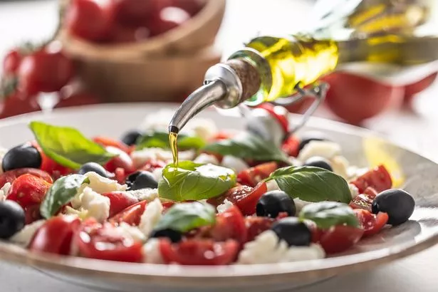 Close-up of pouring olive oil into an Italian Caprese salad