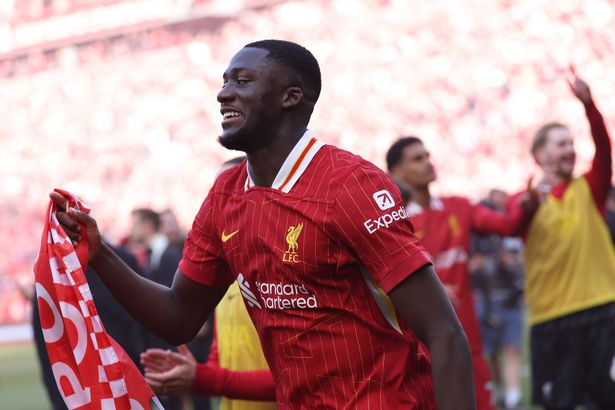 Ibrahima Konate of Liverpool holds a flag, as he celebrates the teams victory and confirmation of winning the Premier League title