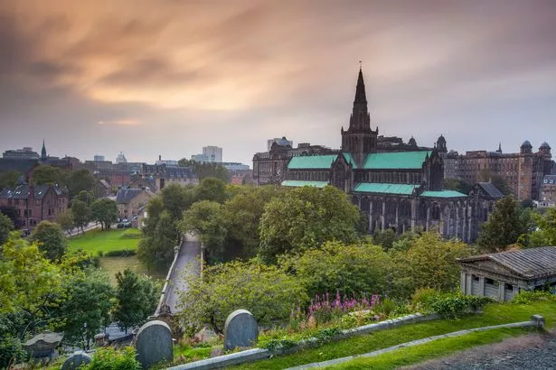 The horizontal long-exposure image of the Glasgow Cathedral and the park taken from Glasglow Necropolis in the cloudy evening just before sunset.