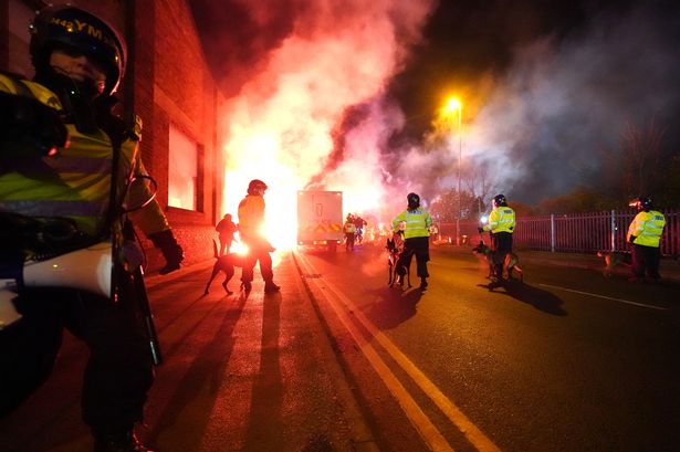 Police officers with dogs approach the scene outside Villa Park as flares are set off outside the stadium before the UEFA Europa Conference League Group E match between Aston Villa and Legia Warsaw