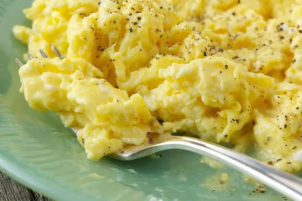 Natural light photo of farm fresh scrambled eggs on green glass plate with antique silver plated for