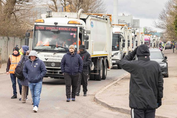 Striking bin men slow walk in front of bin lorries in Redfern Road outside the Atlas council depot in Tyseley, with a queue of bin lorries behind 