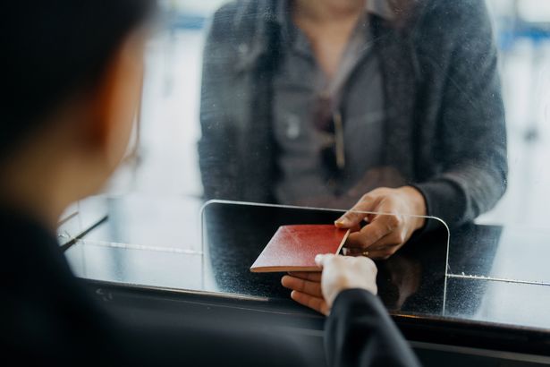 Image of a traveller handing their passport to airport worker