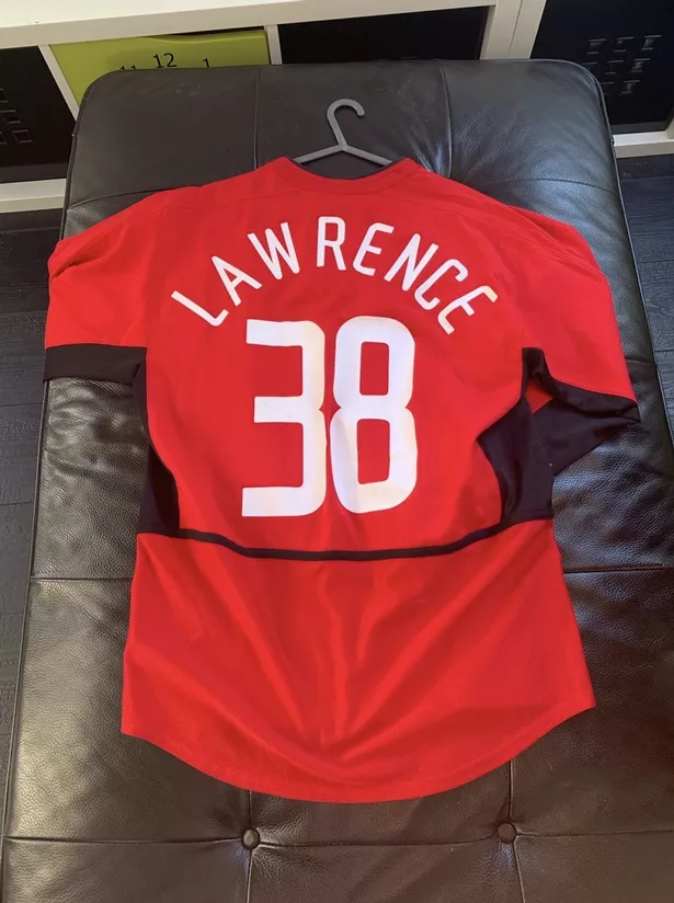 A Manchester United shirt laying frontside down with 'Lawrence' and '38' on the back.