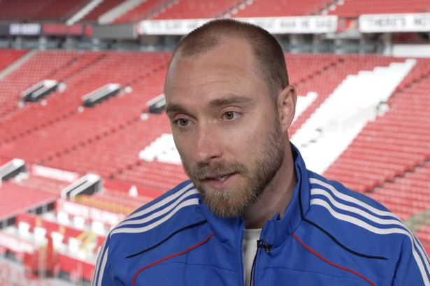 Christian Eriksen conducts a sit-down TV interview at Old Trafford with the East Stand in the background.