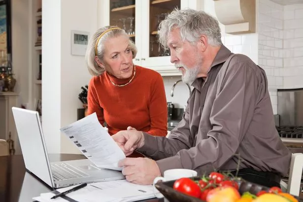 Senior couple looking concerned with bills and laptop