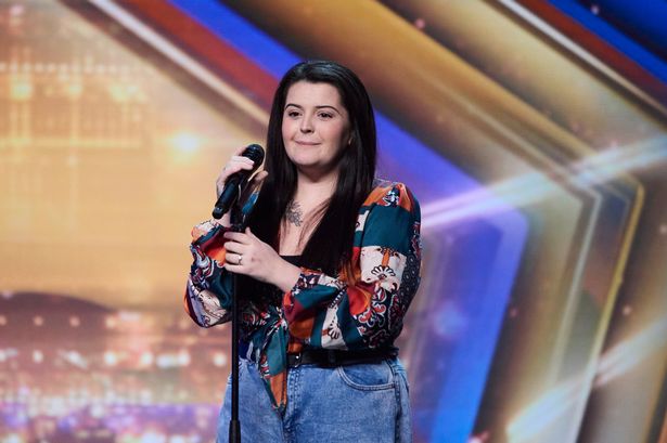 Louise Hall in a black top, floral shirt and blue jeans on the Britain's Got Talent stage with a microphone in an audition.