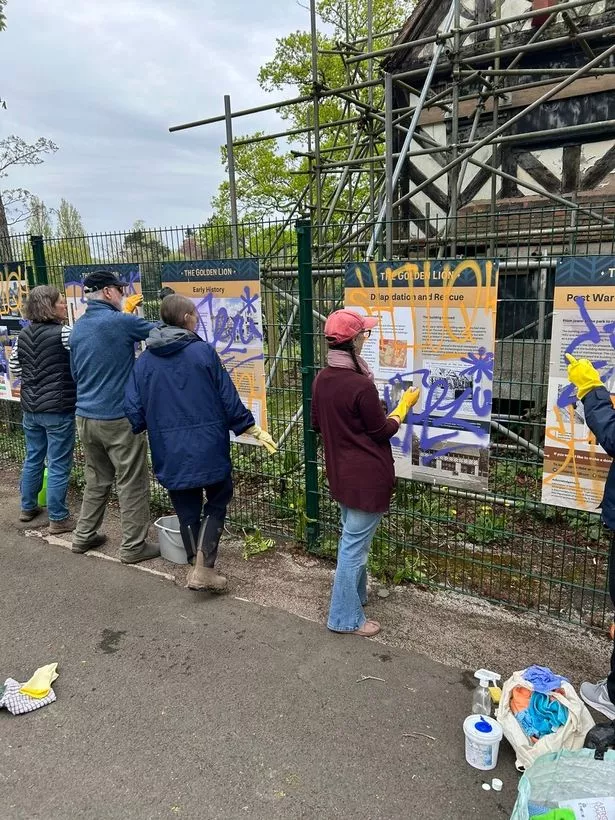 Volunteers cleaning up the graffiti sprayed boards outside the Golden Lion building in Cannon Hill Park