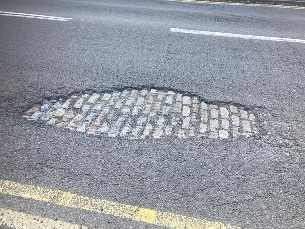 A view of the cobbled streets behind the modern tarmac in St Vincent Street in Birmingham city centre has been revealed by a pothole 