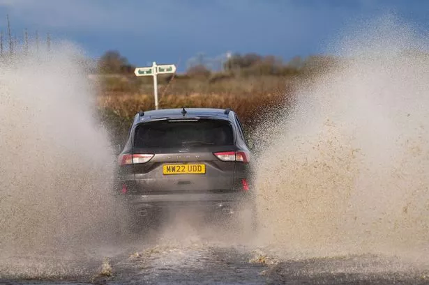 A photo of a car driving through a flood