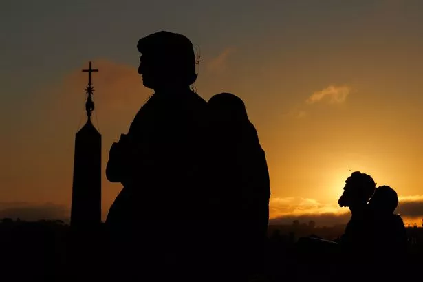 The sun setting in the background of people moving around in the evening light
