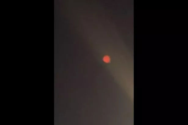 A bright orange glow in the sky amid a string of satellite launches