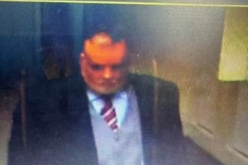 Raymond McCourt last photographed wearing a long black trench, grey waistcoat and trousers, a blue shirt and a red and white tie.