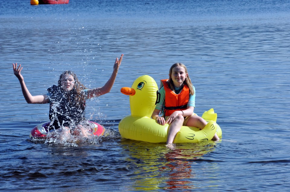 Two girls playing in a lake with inflatable rings.