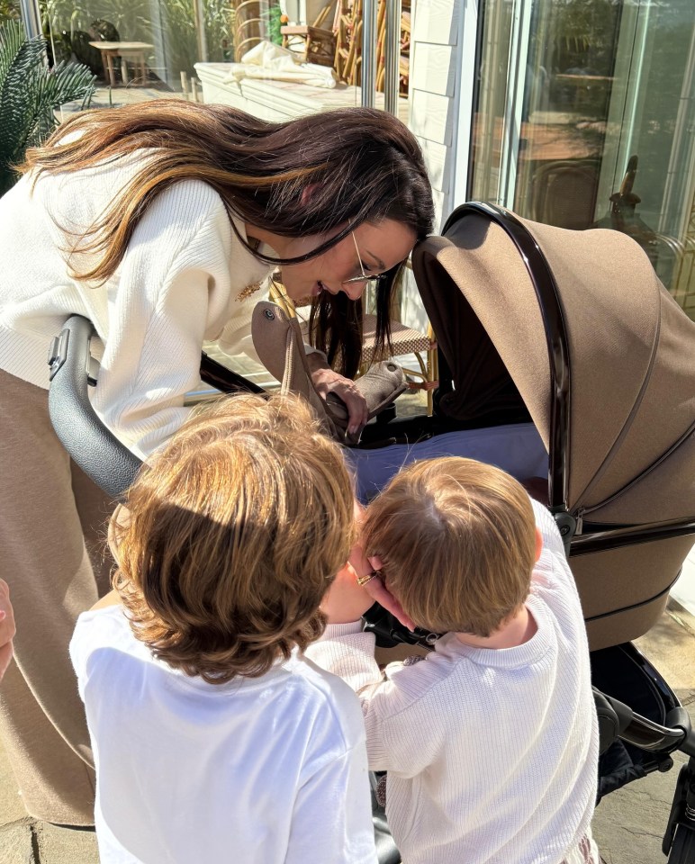 Woman and two children looking into a stroller.