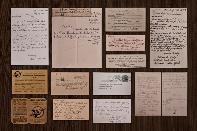 A collection of vintage handwritten letters, postcards, and documents arranged neatly on a wooden surface, showing various handwriting styles and paper types in shades of brown and beige.