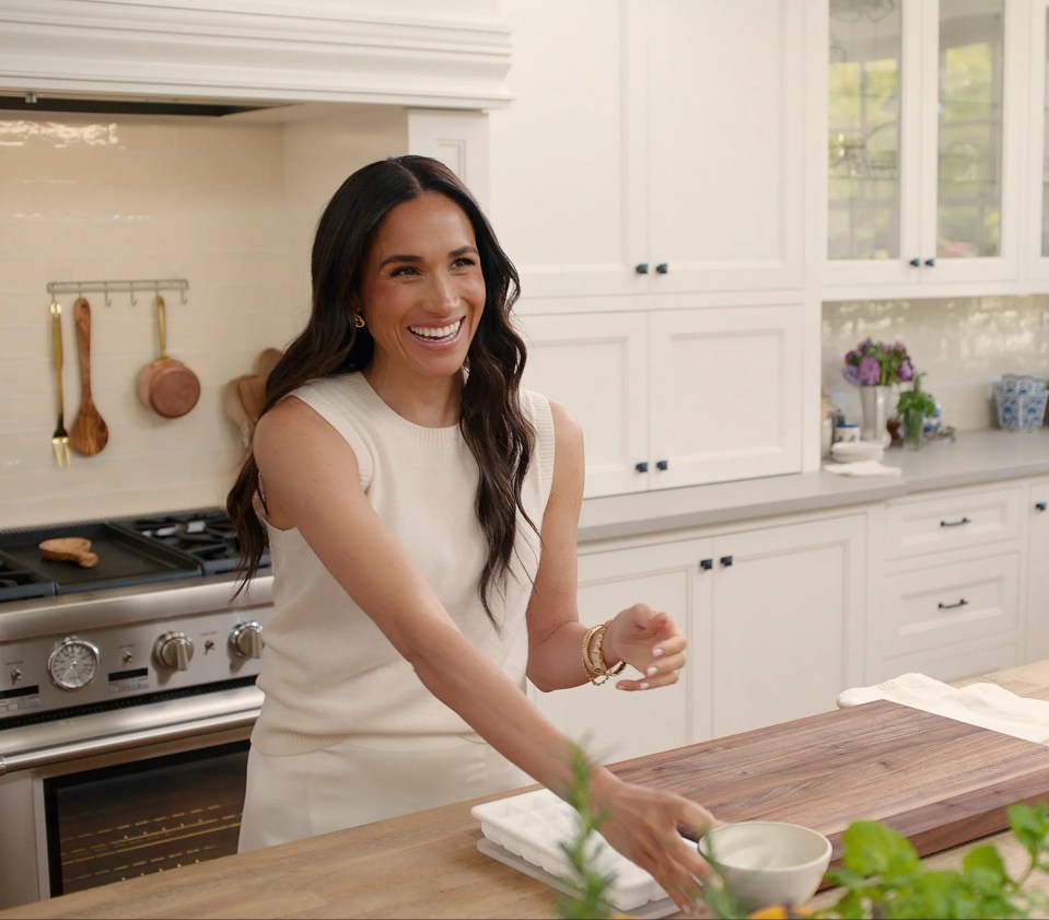 Meghan Markle in a white top in her kitchen.
