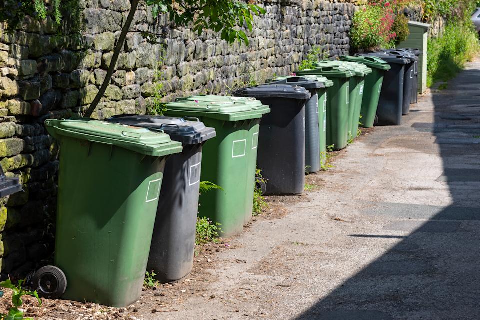Refuse bins lined up opposite a terrace of cottages in Hinchliffe Mill village near Holmfirth, Northern England.