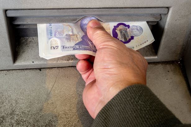 A person using an ATM, or cash machine to withdraw cash bank notes.