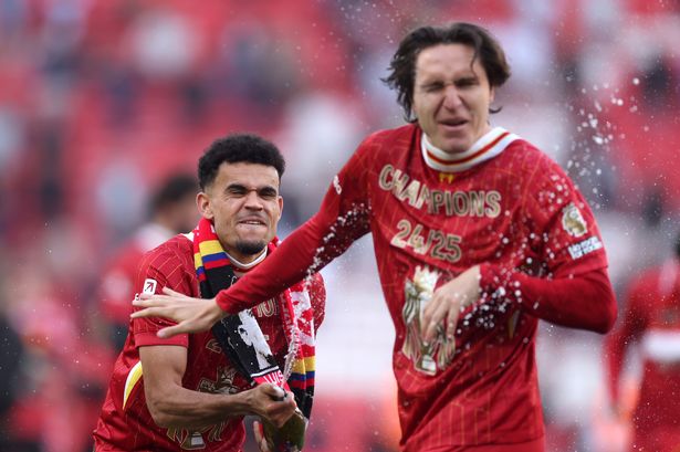 Luis Diaz of Liverpool sprays drink over Federico Chiesa as they celebrate their team's victory and confirmation of winning the Premier League title after the match against Tottenham Hotspur at Anfield on April 27 2025