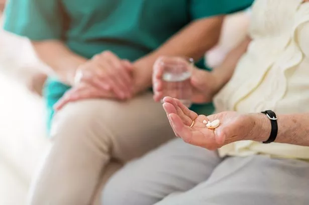 Picture of a nurse consoling an elderly patient who is holding medication in their hand