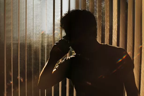 A stock shot of a man on the phone in shadow