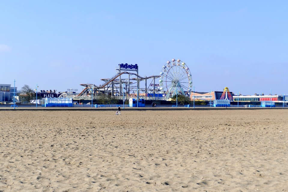 Deserted beach with a funfair in the background.