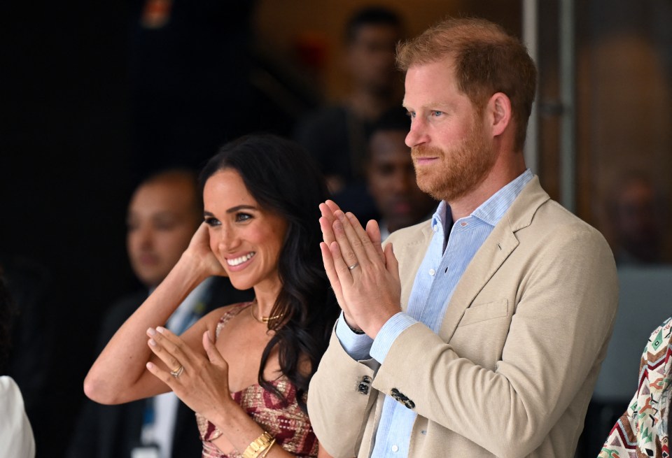 Prince Harry and Meghan Markle clapping at an event.