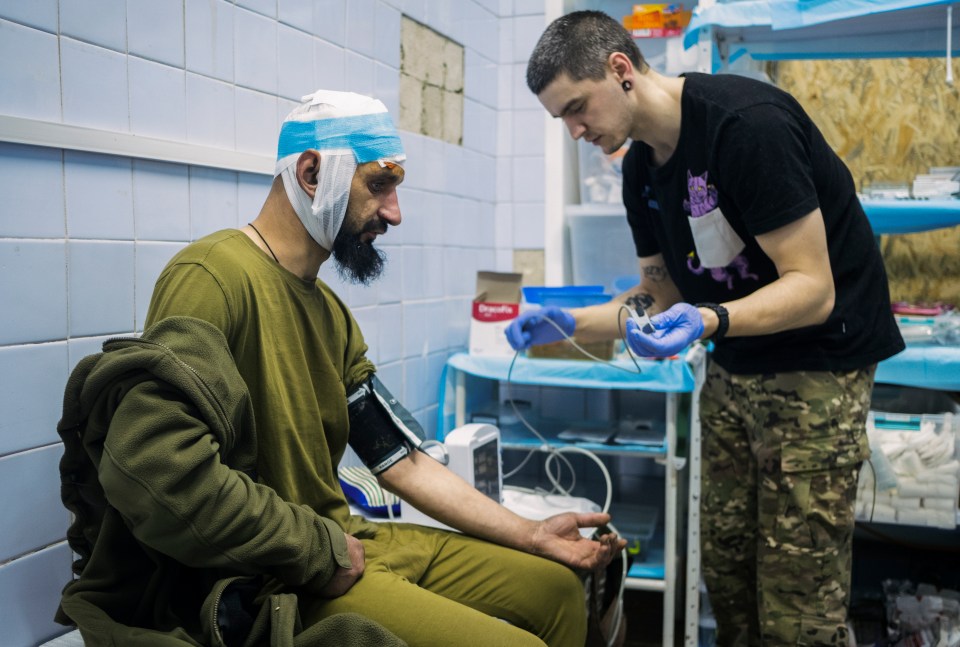 A wounded Ukrainian soldier receives medical attention at a stabilization point.