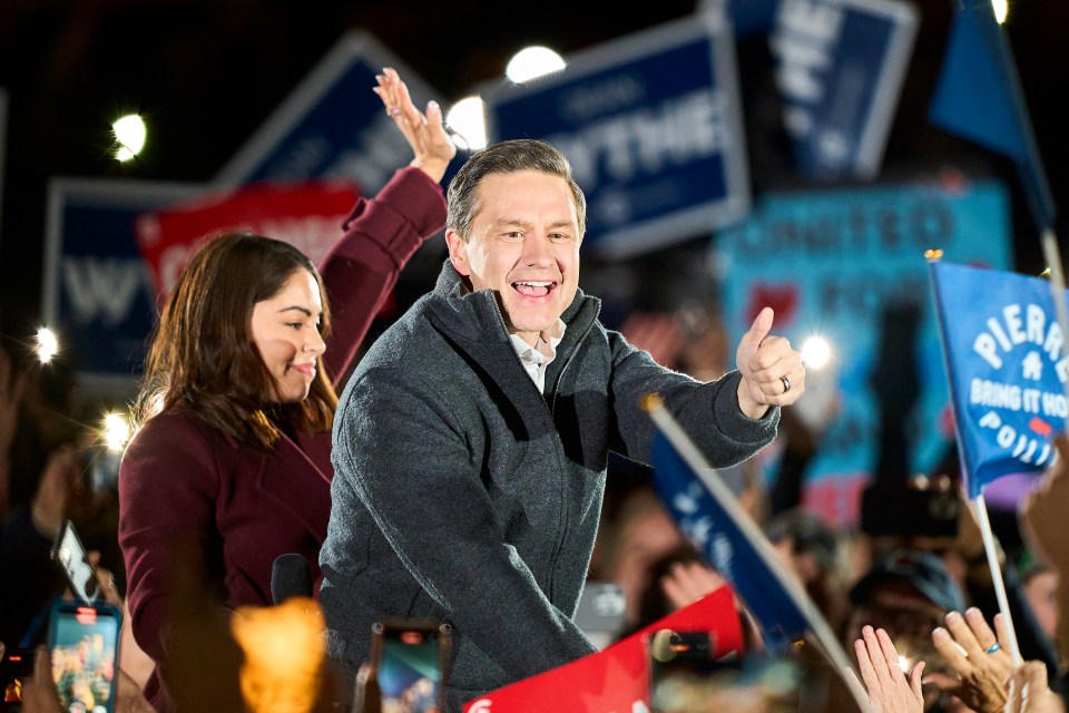 Pierre Poilievre giving a thumbs up at a campaign event with his wife.