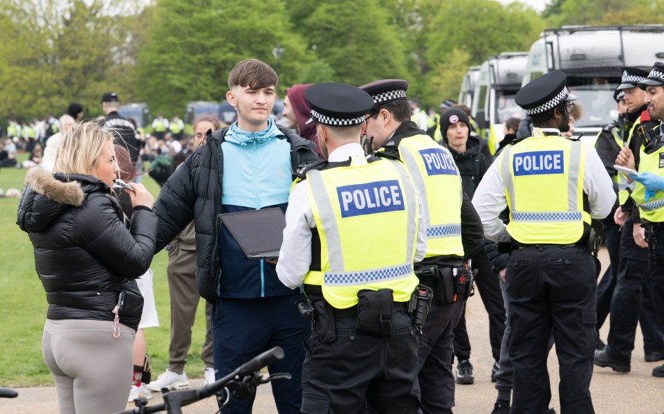 Police officers speaking with a young man at a cannabis legalization protest.
