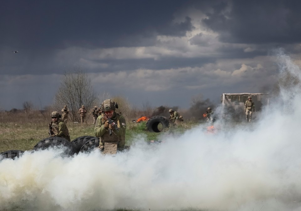 Ukrainian soldiers training amidst smoke and fire.