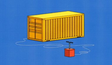 A large yellow shipping container with a detonator device attached to it via visible wires