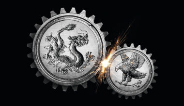 An illustration of two cogs, grinding against each other and causing a spark between them. The larger cog on the left has the image of a Chinese dragon on the side whereas the smaller cog on the right depicts an American eagle.