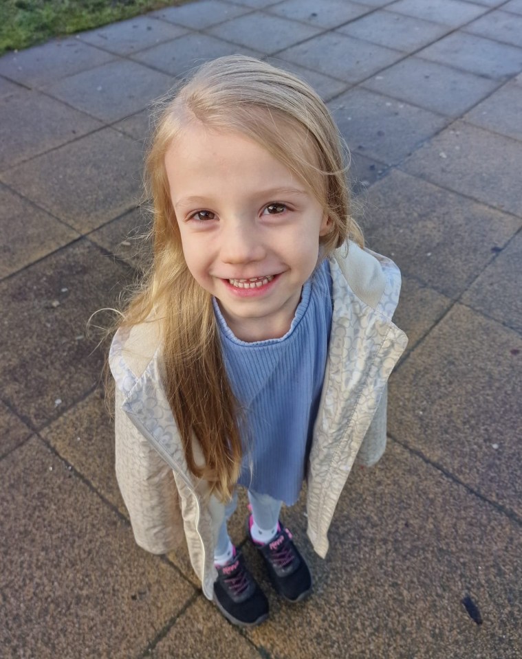 Five-year-old girl smiling outdoors.