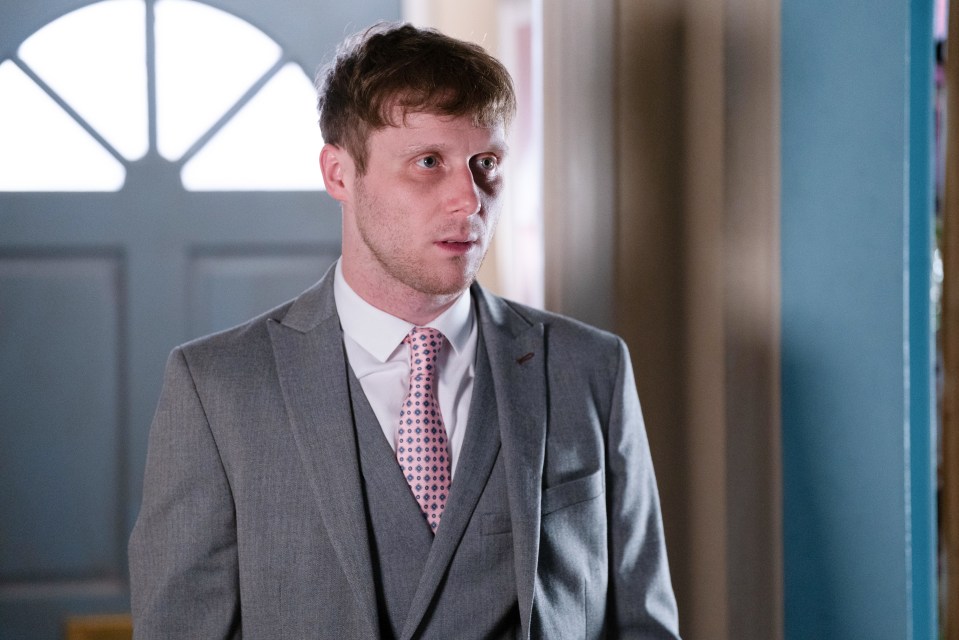 Jay Mitchell from EastEnders in a grey suit.