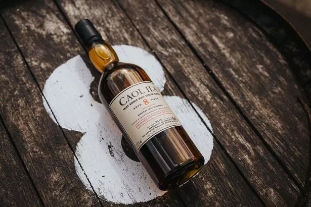 A bottle of Caol Ila 8 Year Old whisky on top of a barrel