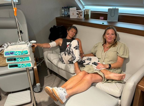Olivia lying on a couch with her mum. She is connected to medical devices